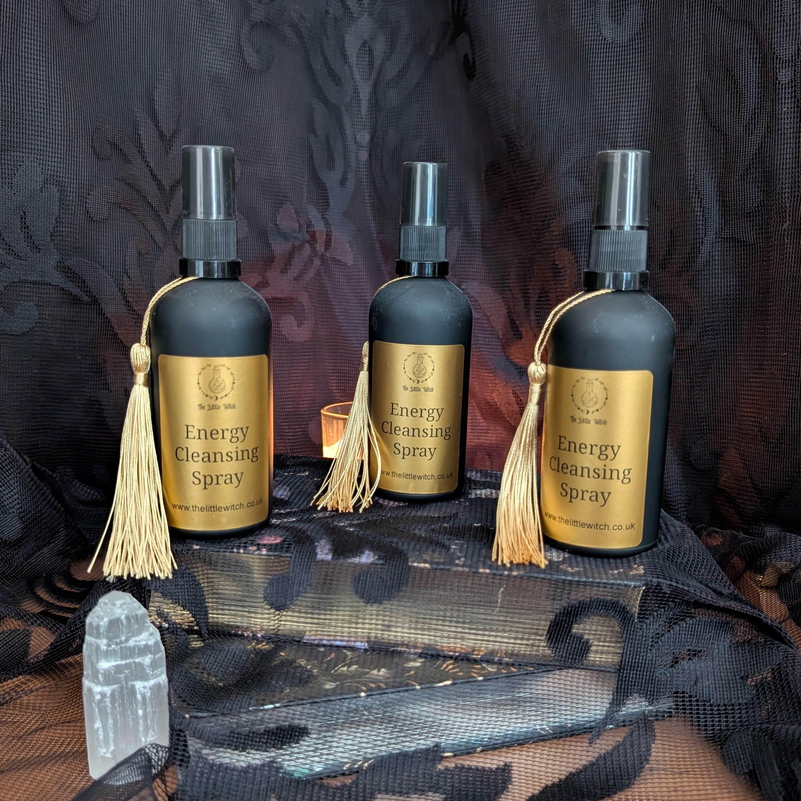 three bottles of energy cleansing spray upon a background of black floral lace