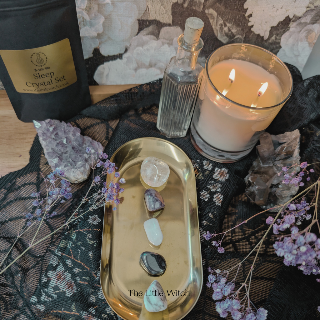 Witchcraft setup with crystal set, candle, and tray on decorative surface.