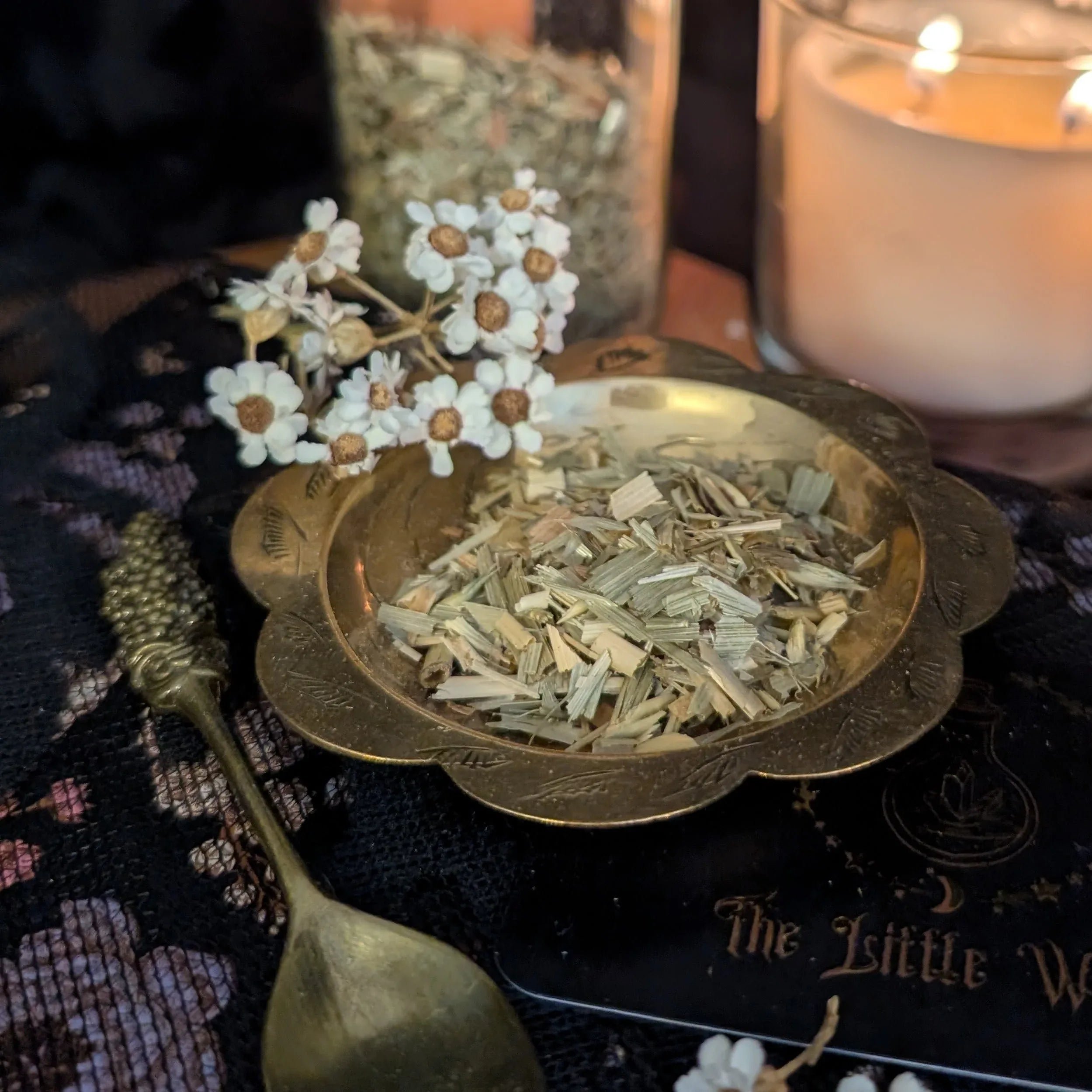 Dried Oat Straw in a bowl with a candle and spoon on a textured surface
