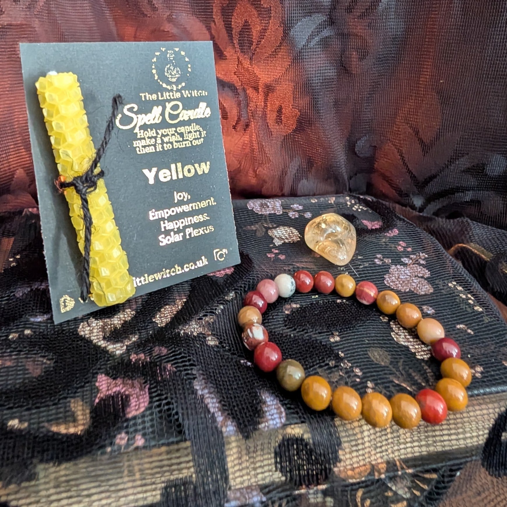 yellow beeswax candle mounted onto The Little Witch branding with a Mookaite bracelet and Citrine tumbled crystal