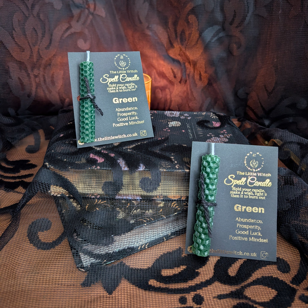 two green beeswax candles mounted on The Little Witch black and gold branded card