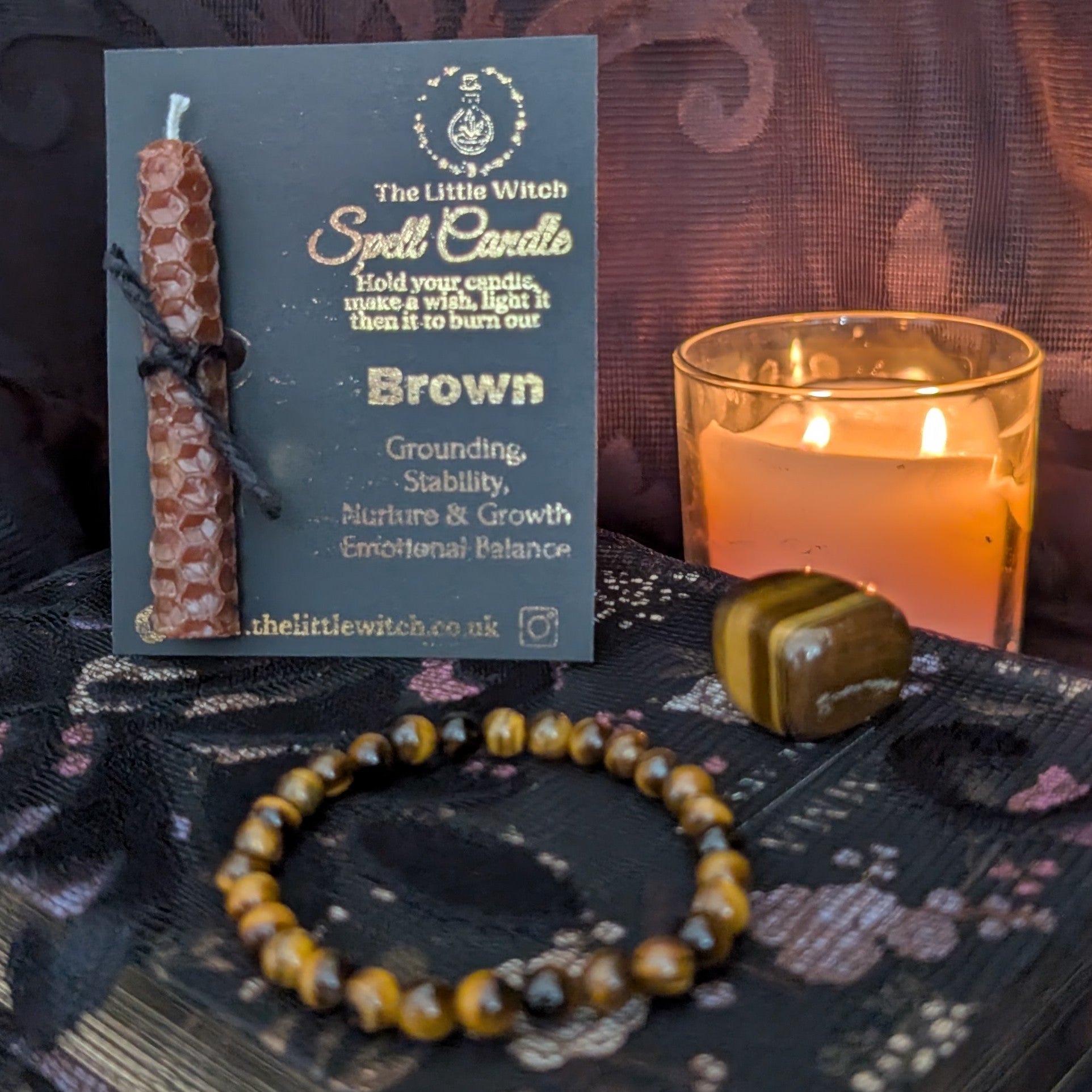  spell candle with a card and bracelet on a dark surface