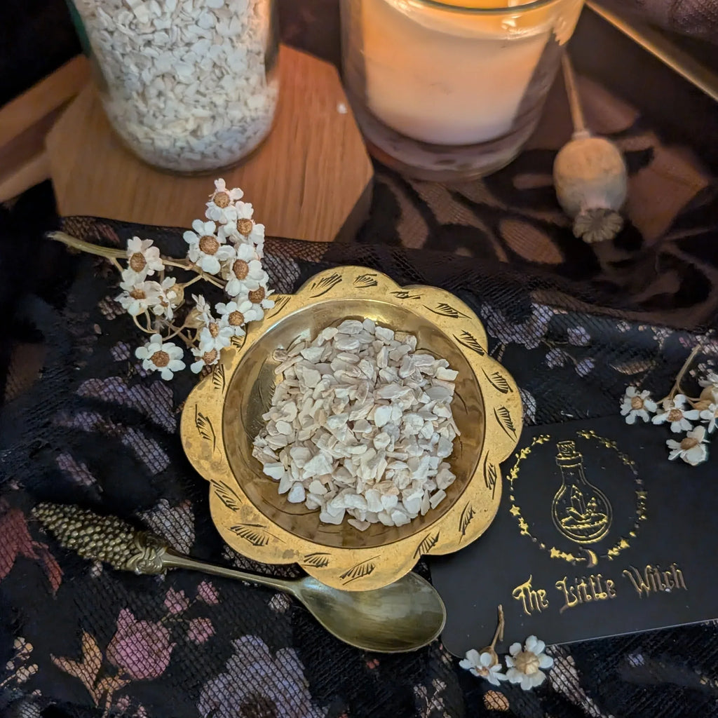 Gold bowl containing dried horseradish on a dark fabric background with 'The Little Witch' branding.