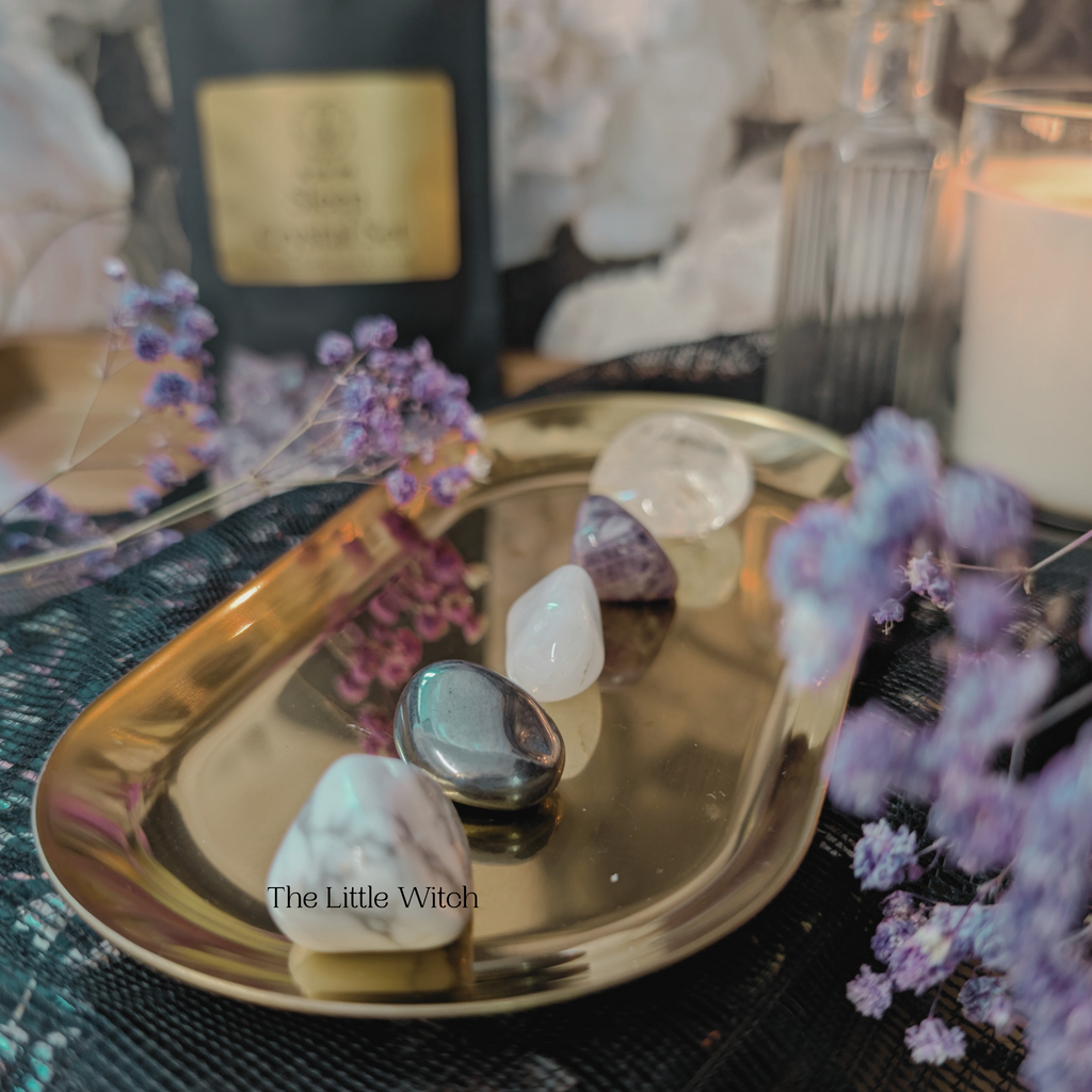 Decorative tray with crystals and purple flowers on a mystical background.
