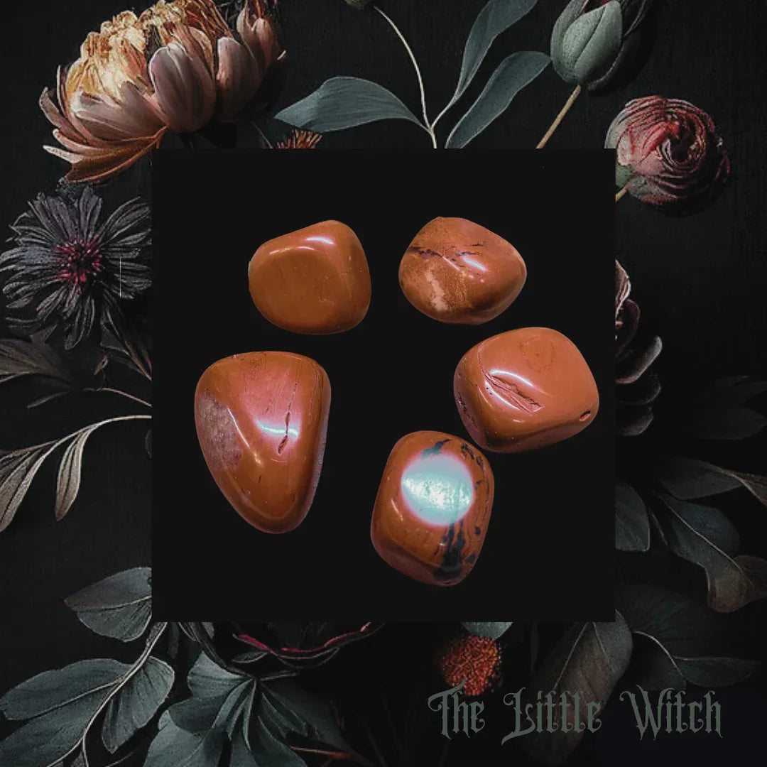 Five orange stones on a dark surface with flowers and leaves around, branded 'The Little Witch'.