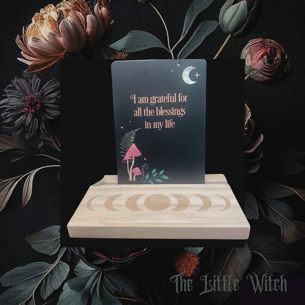 affirmation card that reads 'I am grateful for all the blessings in my life' sitting in a wooden stand engraved with the moon phases