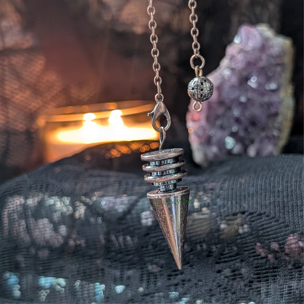 metal pendulum on a chain against a mystical background with crystals and fire.