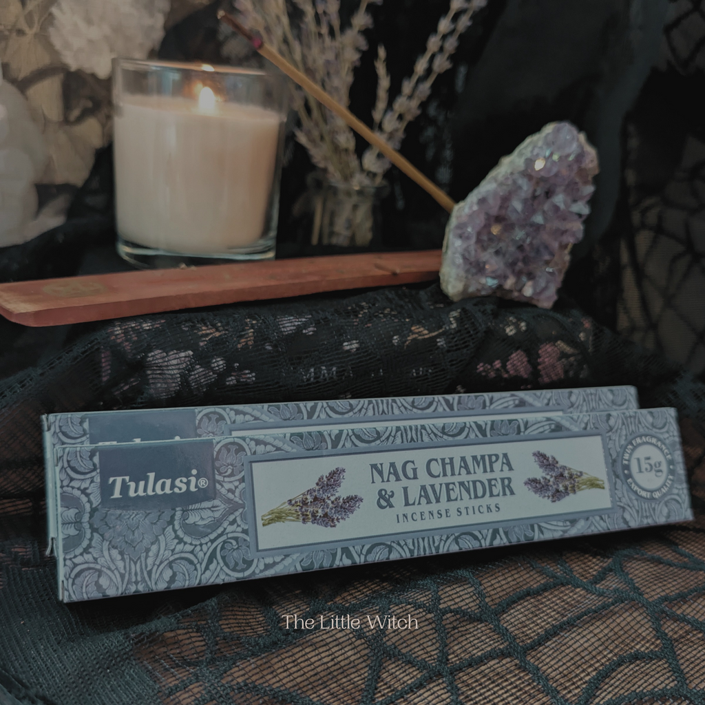 Tulasi Nag Champa & Lavender incense sticks with a candle and crystal on a dark surface.