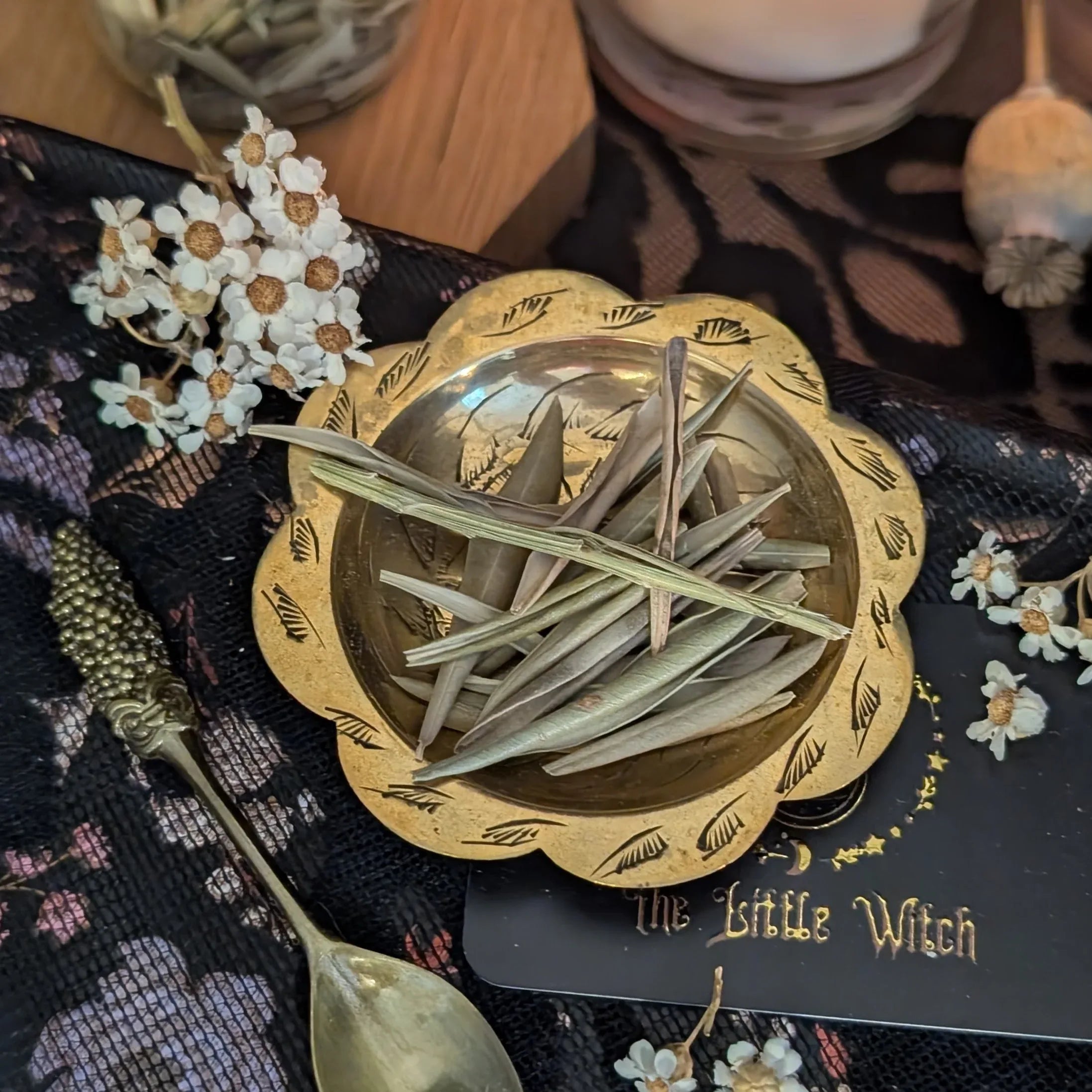 Decorative gold bowl with dried Olive leaves herbs on a black surface with floral patterns