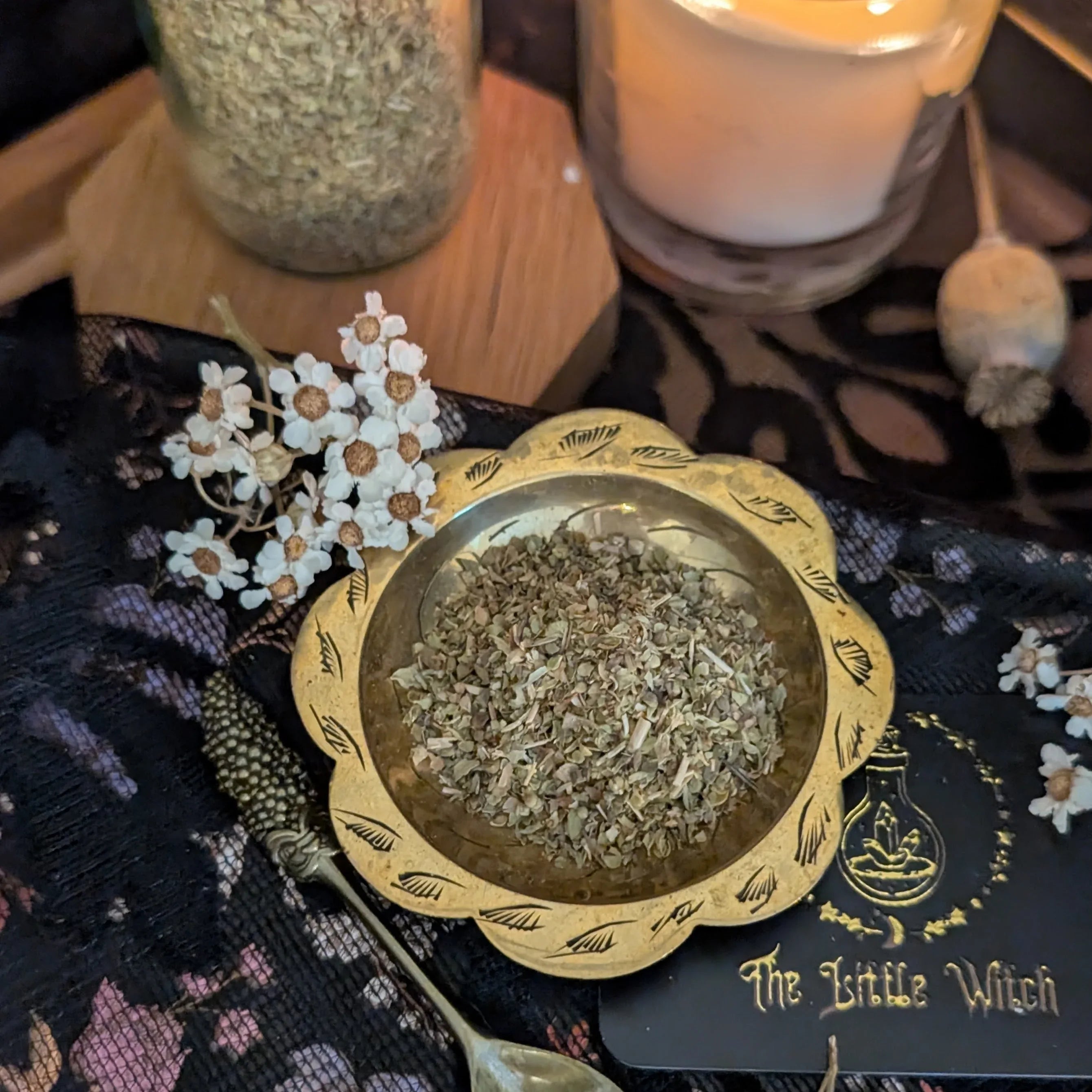 Dried Oregano in a decorative bowl on a black lace surface with 'The Little Witch' branding.