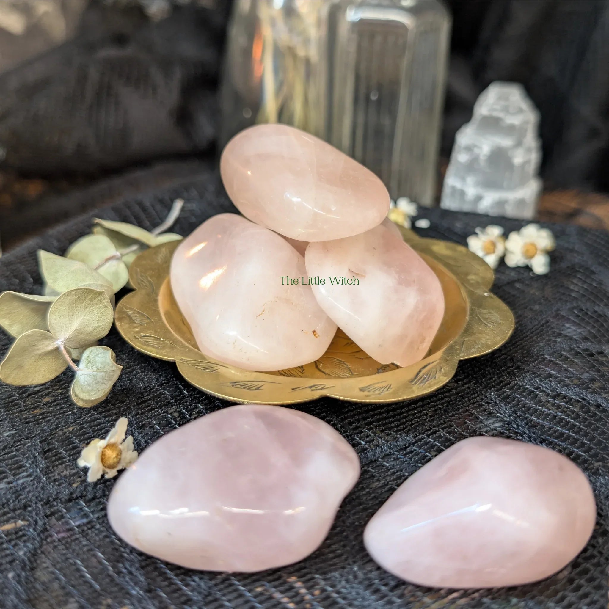 rose quartz on a gold dish with decorative elements on a dark surface