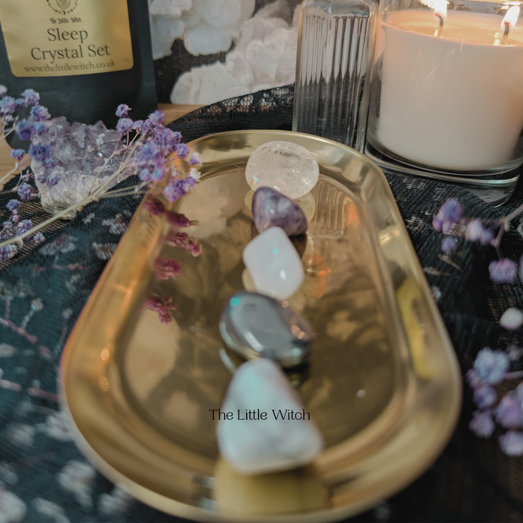 Crystal set on a gold tray with a candle and flowers in the background.