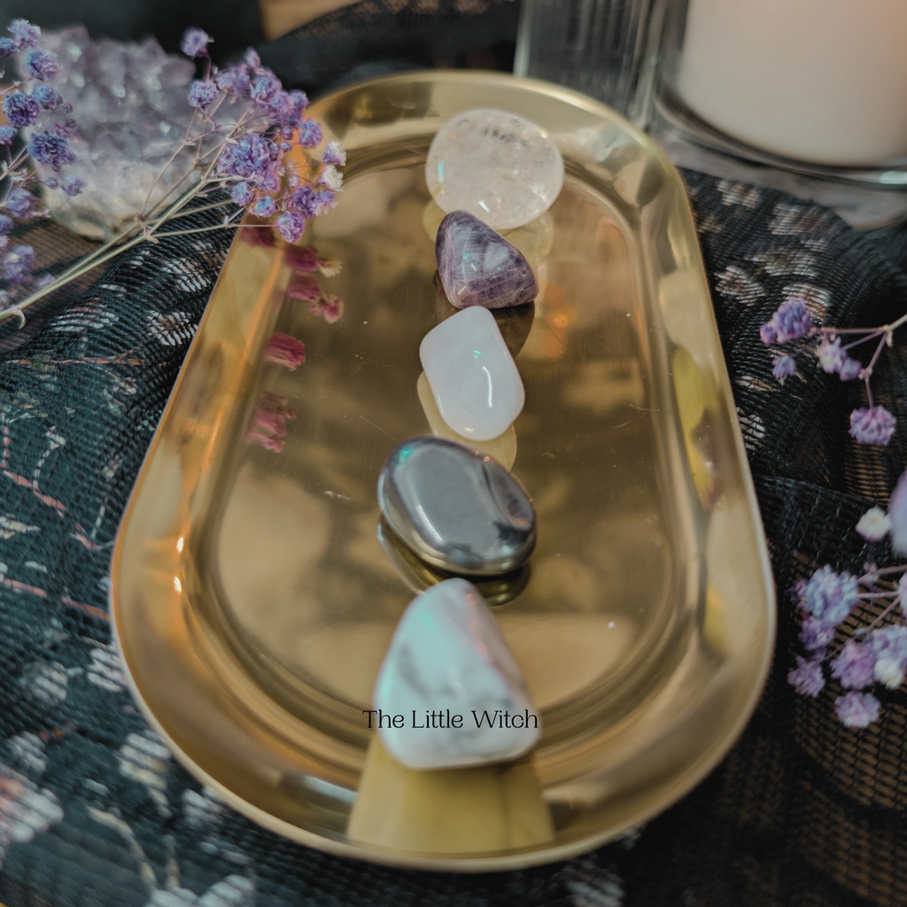 Gold tray with crystals and dried flowers on a textured surface