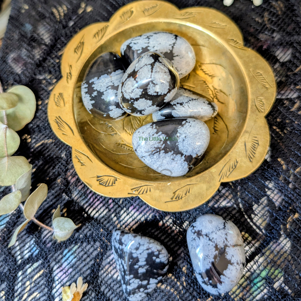 Decorative gold bowl with white marbled stones on a textured black fabric background