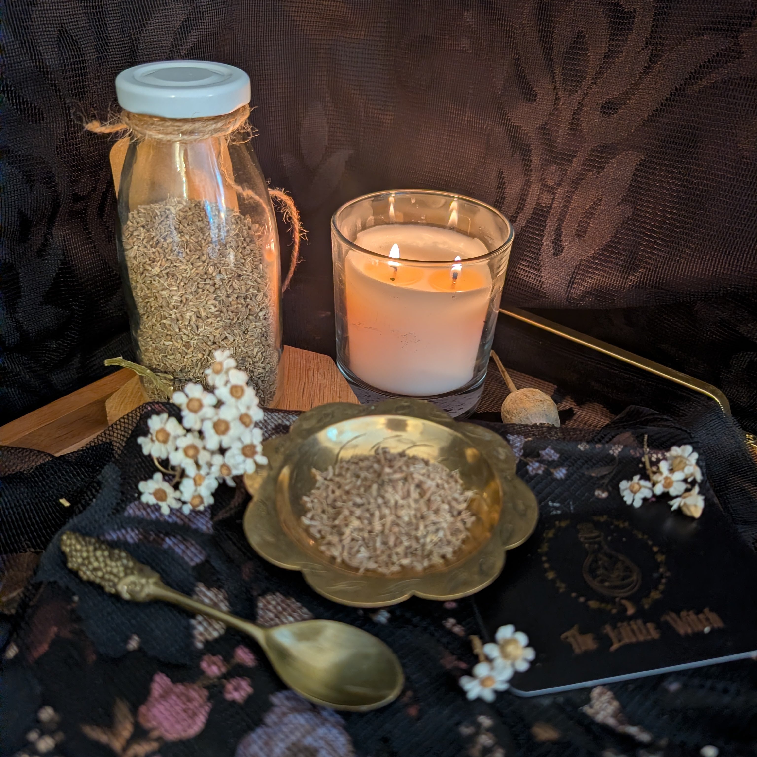 Candle, jar, and decorative items on a dark surface with a patterned background